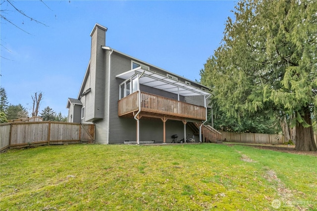 rear view of property with a fenced backyard, a chimney, stairs, a deck, and a lawn