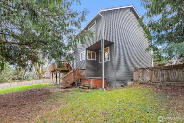 rear view of house with fence, stairway, a wooden deck, a lawn, and a gate