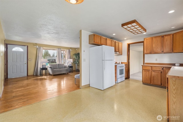 kitchen featuring open floor plan, recessed lighting, white appliances, light countertops, and light floors