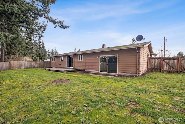 rear view of house with a wooden deck, a yard, a fenced backyard, and a chimney