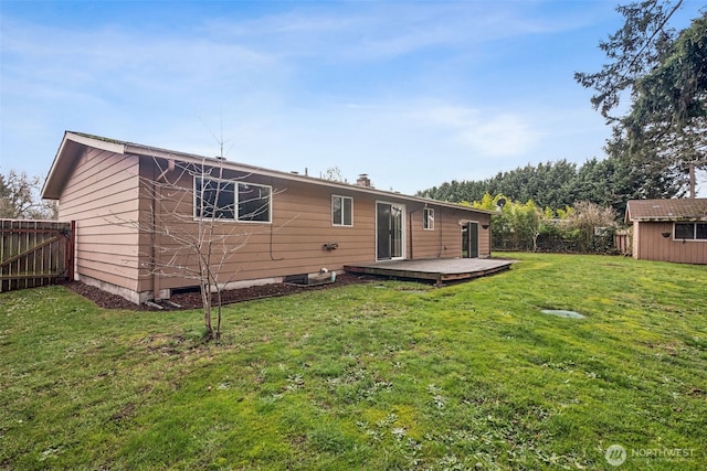 rear view of house with an outbuilding, a lawn, and fence