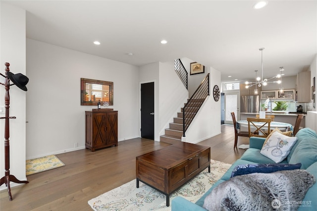 living area with baseboards, stairway, wood finished floors, a chandelier, and recessed lighting