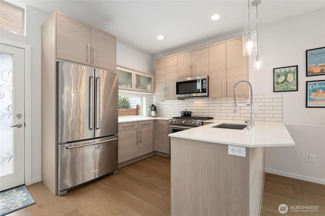 kitchen with tasteful backsplash, a sink, a peninsula, and high quality appliances