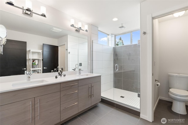 full bathroom featuring double vanity, a stall shower, toilet, tile patterned floors, and a sink