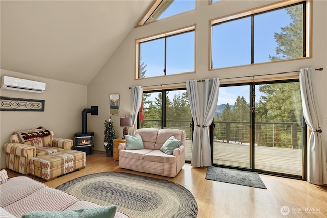 living room with a wall unit AC, a wood stove, high vaulted ceiling, and wood finished floors