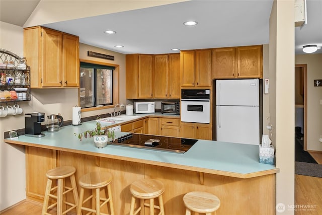 kitchen with recessed lighting, a peninsula, a sink, a kitchen breakfast bar, and black appliances