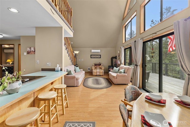 living area featuring a towering ceiling, stairway, light wood finished floors, and recessed lighting