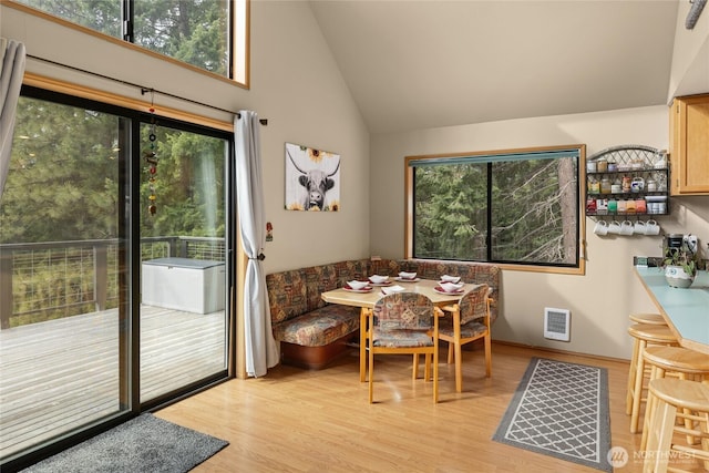 dining room with lofted ceiling, breakfast area, light wood-type flooring, and visible vents