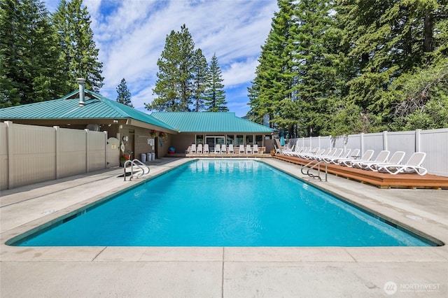 community pool with a patio area and fence