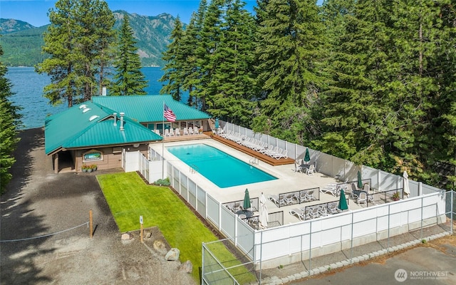 community pool featuring a patio, a yard, a fenced backyard, and a water and mountain view