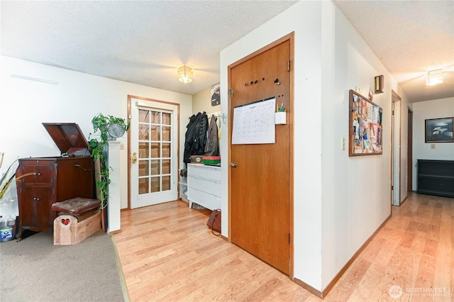 hall featuring wood finished floors, baseboards, and a textured ceiling