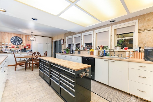 kitchen featuring black dishwasher, white cabinetry, a sink, butcher block countertops, and dark cabinetry