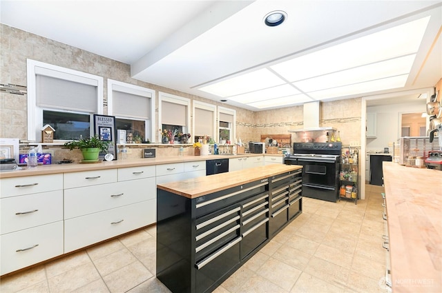 kitchen with dark cabinets, butcher block counters, white cabinets, wall chimney range hood, and black appliances