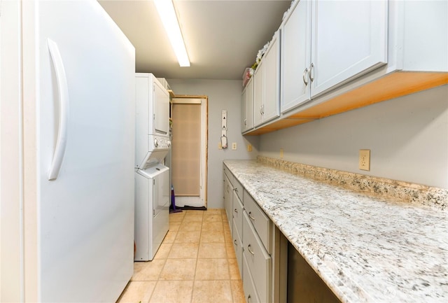 laundry room with light tile patterned flooring, cabinet space, and stacked washer / drying machine