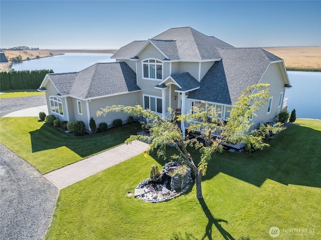 view of front of home featuring a shingled roof, a front yard, decorative driveway, and a water view