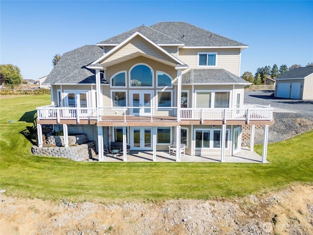back of property with a deck, a shingled roof, french doors, a lawn, and a patio area