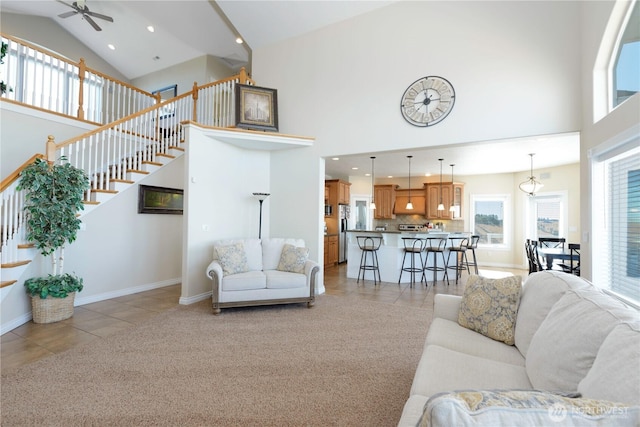 living room with light tile patterned floors, high vaulted ceiling, light colored carpet, baseboards, and stairway