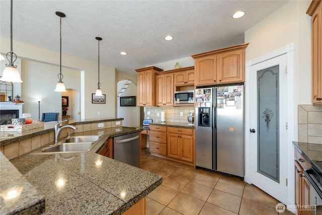 kitchen featuring backsplash, a fireplace, stainless steel appliances, and a sink