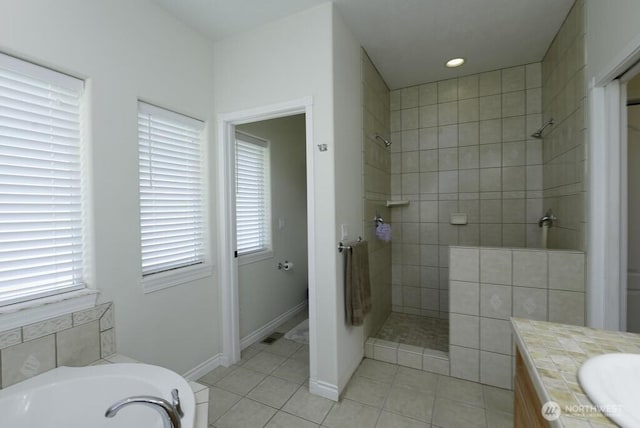 bathroom featuring tile patterned flooring, a garden tub, baseboards, and walk in shower
