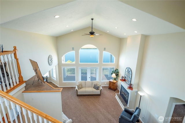 living room with recessed lighting, high vaulted ceiling, carpet flooring, and a glass covered fireplace