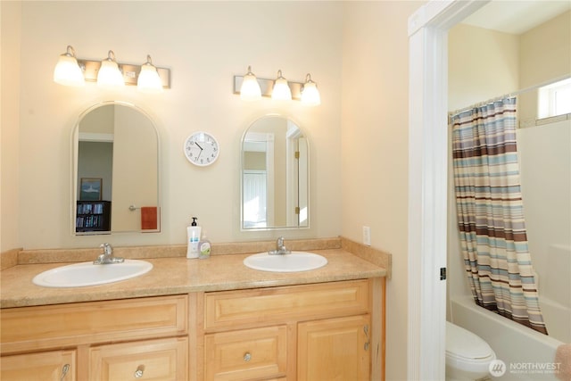 bathroom with double vanity, shower / bath combo, a sink, and toilet