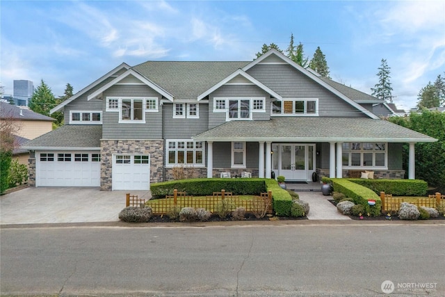 view of front facade featuring french doors, roof with shingles, concrete driveway, a garage, and stone siding