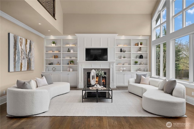 living room with a glass covered fireplace, baseboards, a high ceiling, and wood finished floors