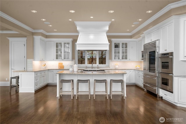 kitchen featuring white cabinets, a kitchen bar, light stone countertops, and stainless steel appliances