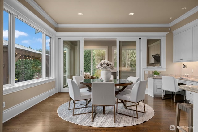 dining space with dark wood-type flooring, crown molding, and baseboards