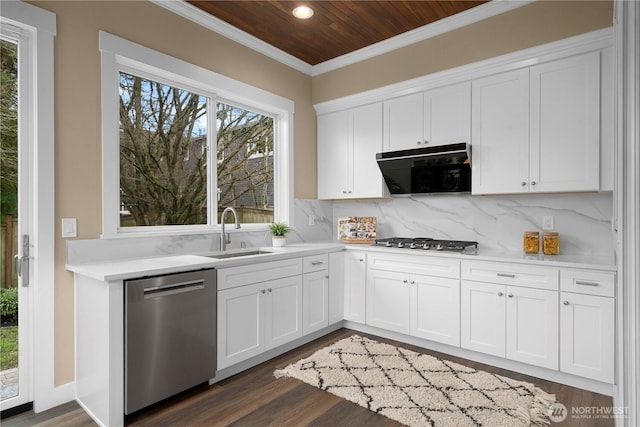 kitchen with dark wood-style floors, stainless steel appliances, backsplash, a sink, and crown molding