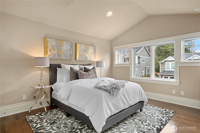 bedroom featuring wood finished floors, vaulted ceiling, baseboards, and multiple windows
