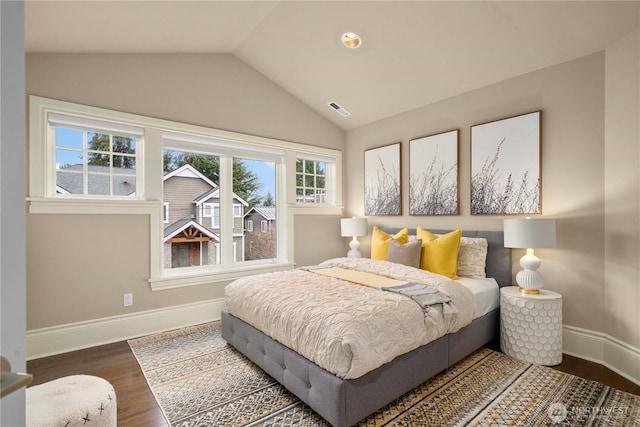 bedroom with lofted ceiling, visible vents, baseboards, and wood finished floors