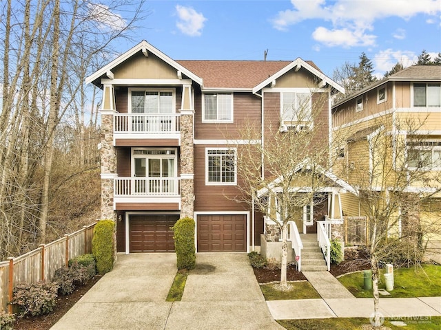 view of front facade with driveway, a garage, a shingled roof, a balcony, and fence