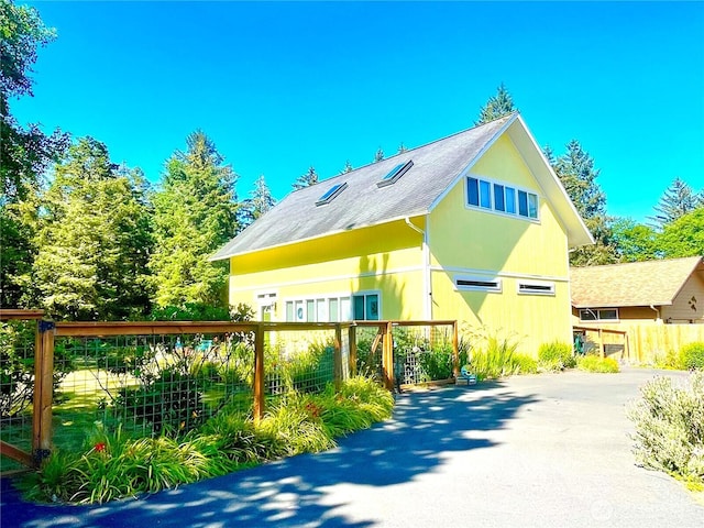 view of property exterior with driveway and fence