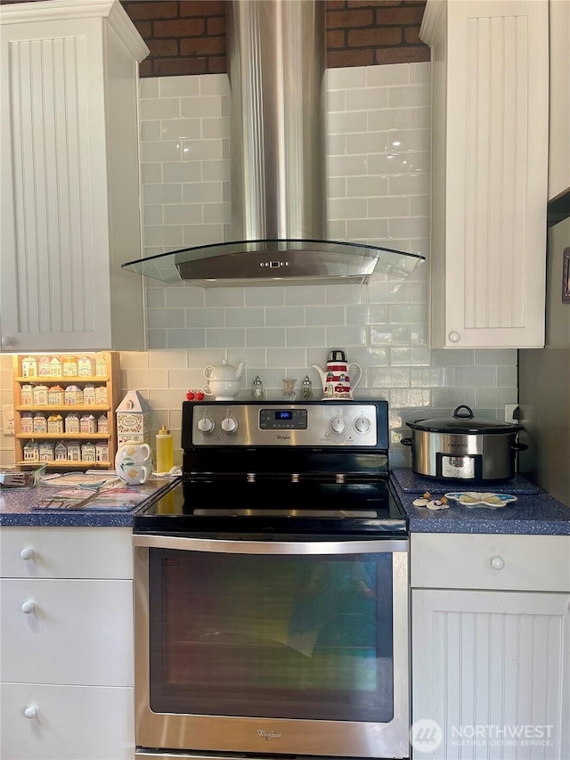 kitchen with white cabinets, wall chimney range hood, backsplash, stainless steel electric range oven, and dark countertops