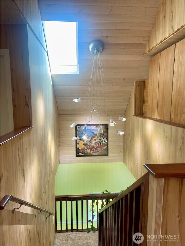 stairway with wooden ceiling, carpet flooring, vaulted ceiling, and wooden walls