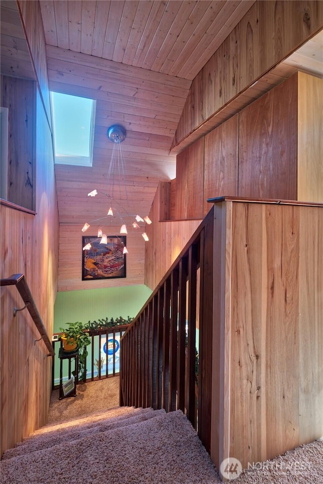 stairway with lofted ceiling, wood walls, wood ceiling, and carpet flooring