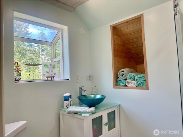 half bathroom with wooden ceiling, vaulted ceiling, vanity, and toilet