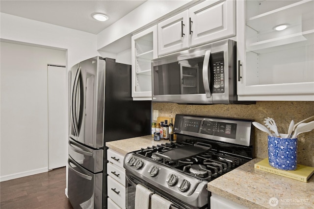 kitchen with dark wood-type flooring, white cabinets, light countertops, appliances with stainless steel finishes, and backsplash