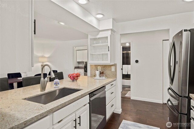 kitchen with light stone counters, a sink, white cabinetry, appliances with stainless steel finishes, and dark wood finished floors