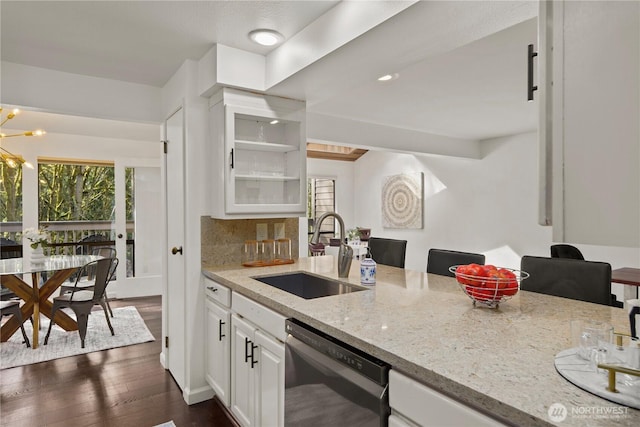 kitchen with dark wood finished floors, dishwashing machine, light stone counters, white cabinetry, and a sink