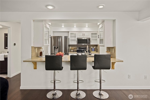 kitchen featuring appliances with stainless steel finishes, a peninsula, and tasteful backsplash