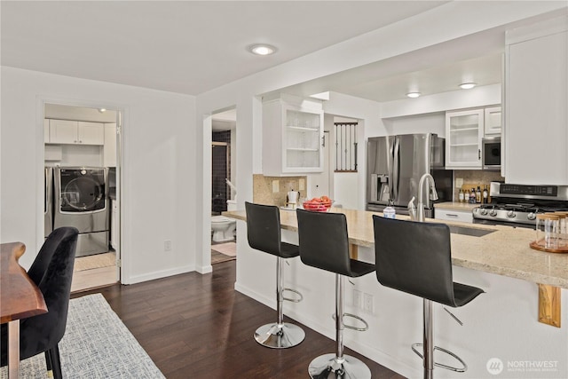 kitchen with glass insert cabinets, light stone counters, stainless steel appliances, and backsplash