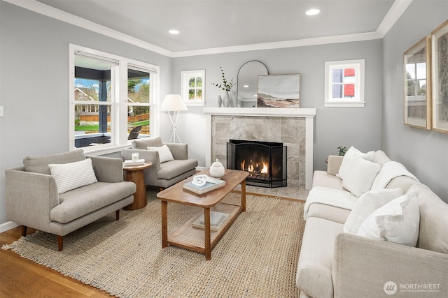 living area with recessed lighting, light wood-style flooring, a high end fireplace, and crown molding