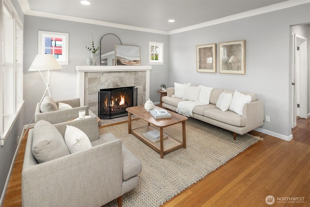 living area with baseboards, recessed lighting, a high end fireplace, wood-type flooring, and crown molding