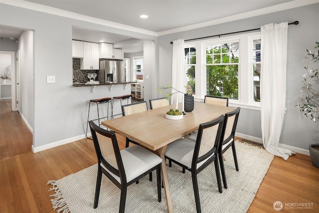 dining room with light wood finished floors, recessed lighting, crown molding, and baseboards