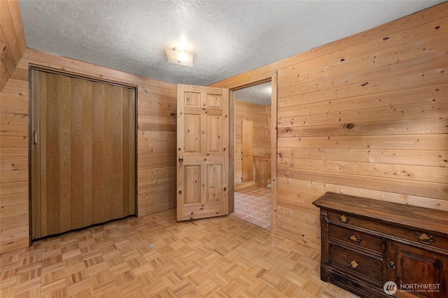 unfurnished bedroom featuring wood walls, a closet, and a textured ceiling