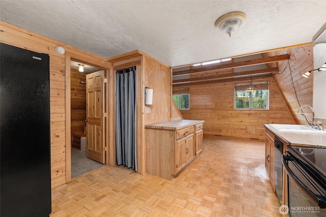 kitchen with dishwashing machine, wood walls, a textured ceiling, and a sink