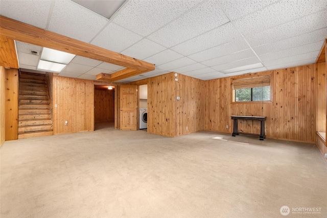 below grade area featuring wooden walls, washer / clothes dryer, light colored carpet, and stairway