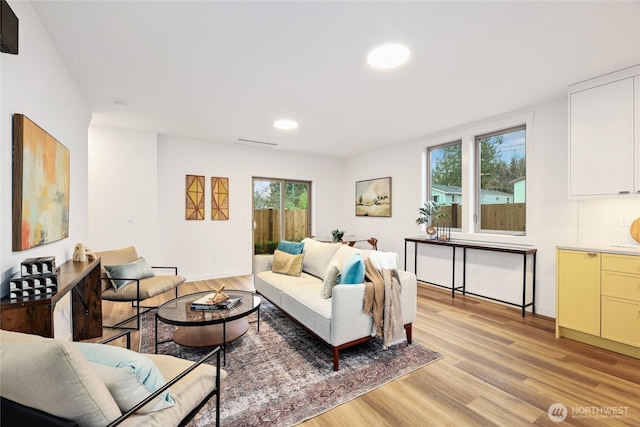 living area featuring light wood-type flooring, plenty of natural light, baseboards, and recessed lighting